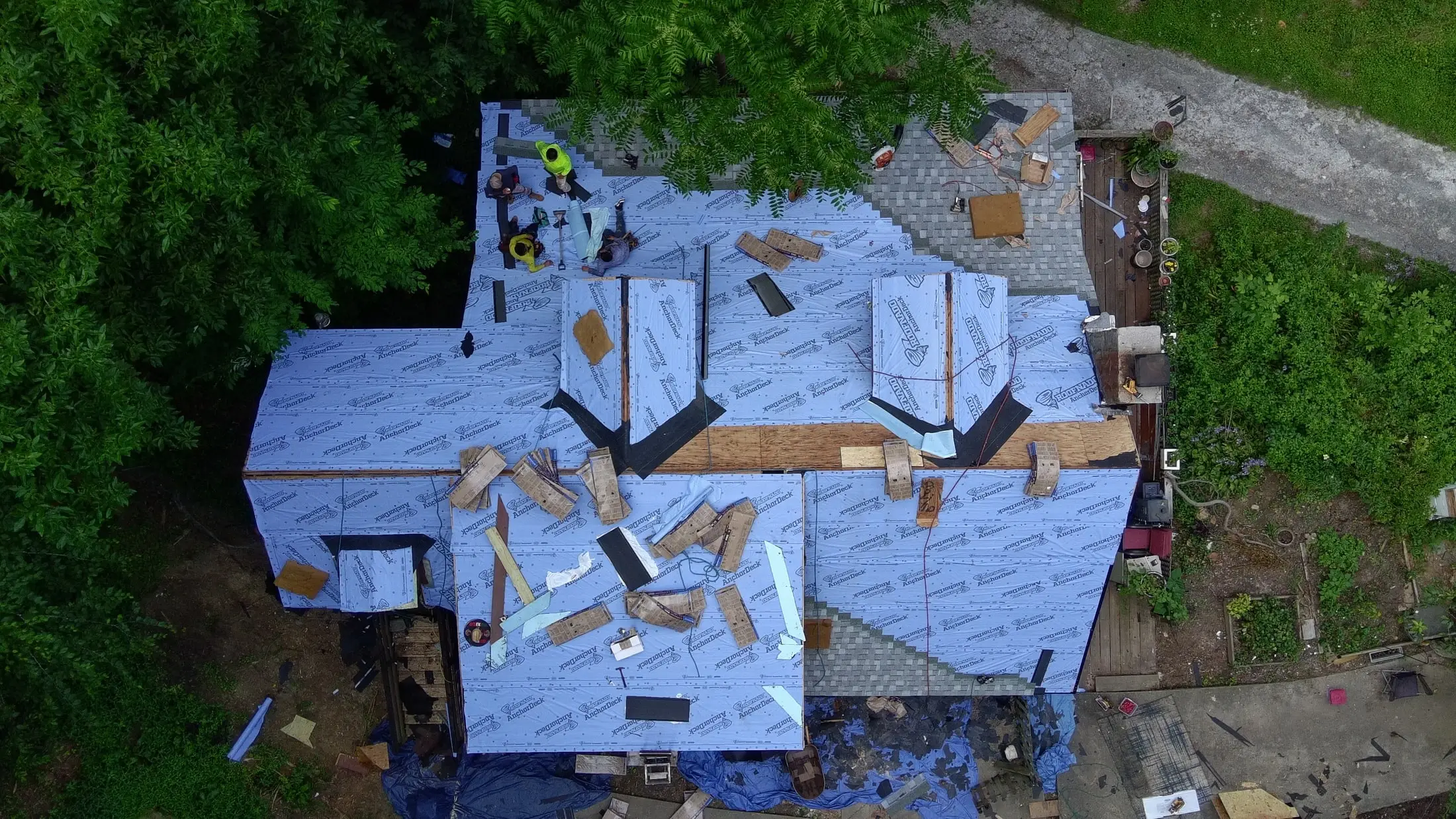 Iron Ridge crew installing new underlayment, with tarps protecting the yard below