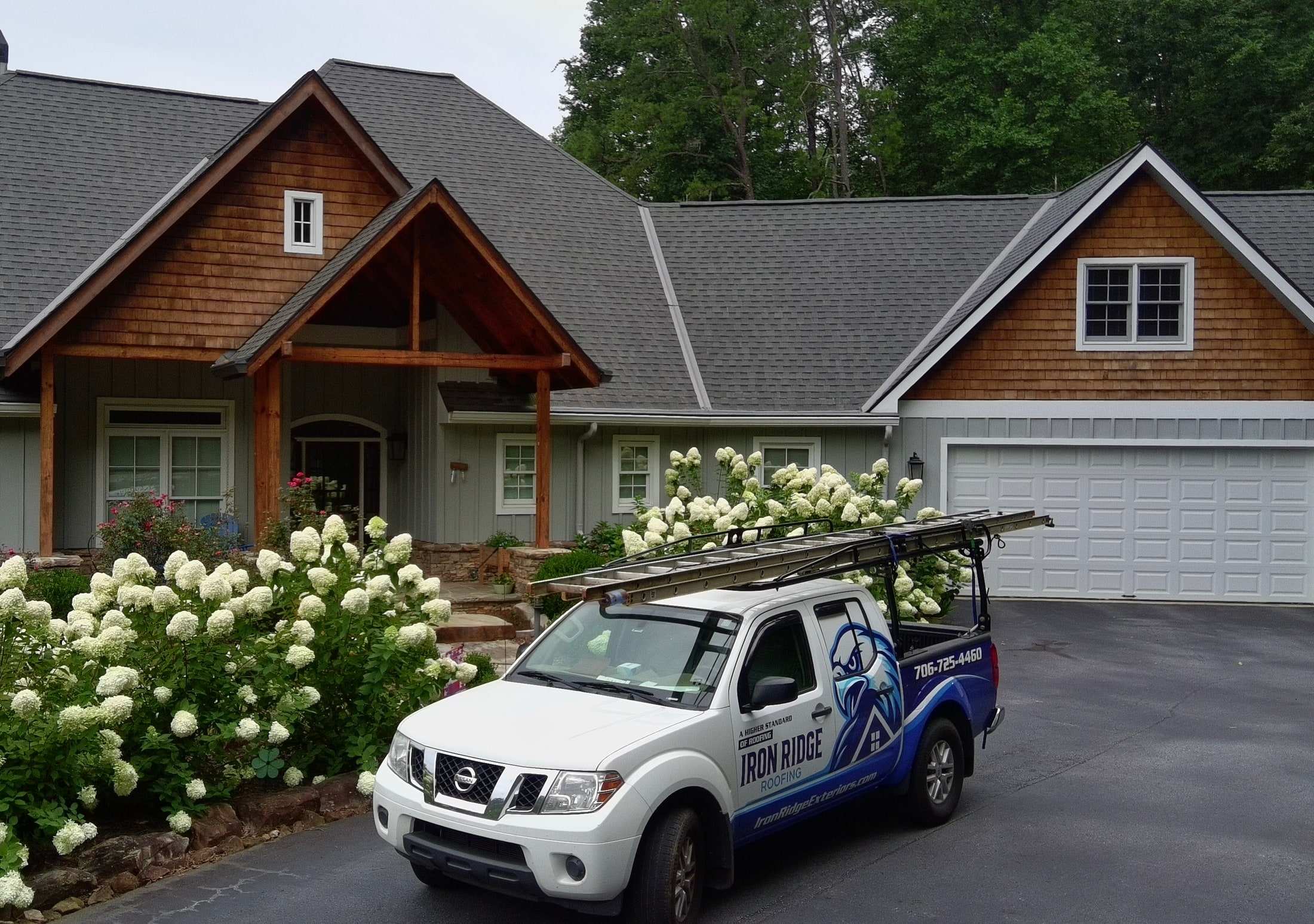 Iron Ridge Roofing truck parked in front of a craftsman-style home with a newly installed gray shingle roof