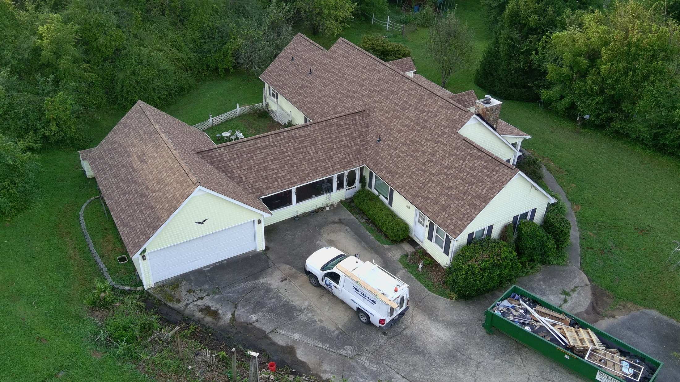 Aerial view of a home with a new brown shingle roof and the Iron Ridge truck on site