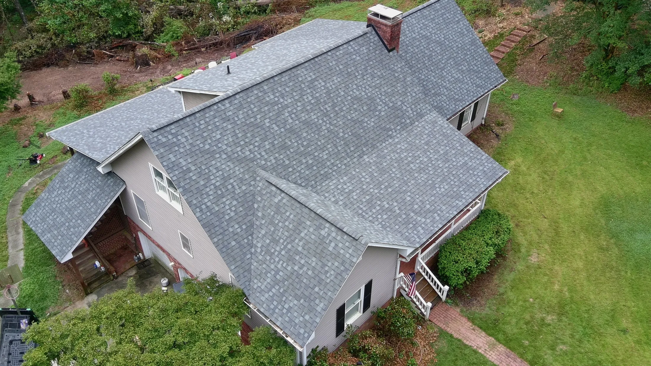 New gray architectural shingle roof on a two-story home with a brick chimney