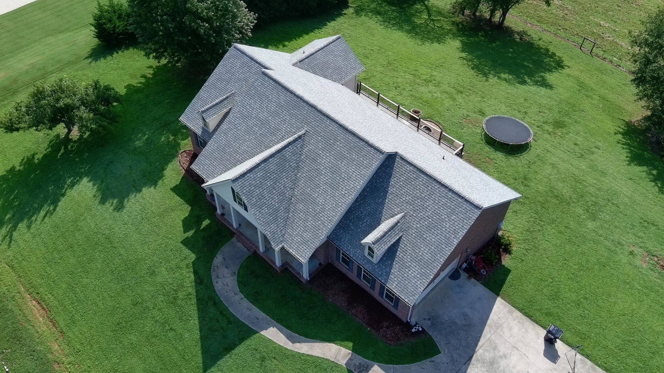 Aerial view of a brick home with a newly replaced gray architectural shingle roof
