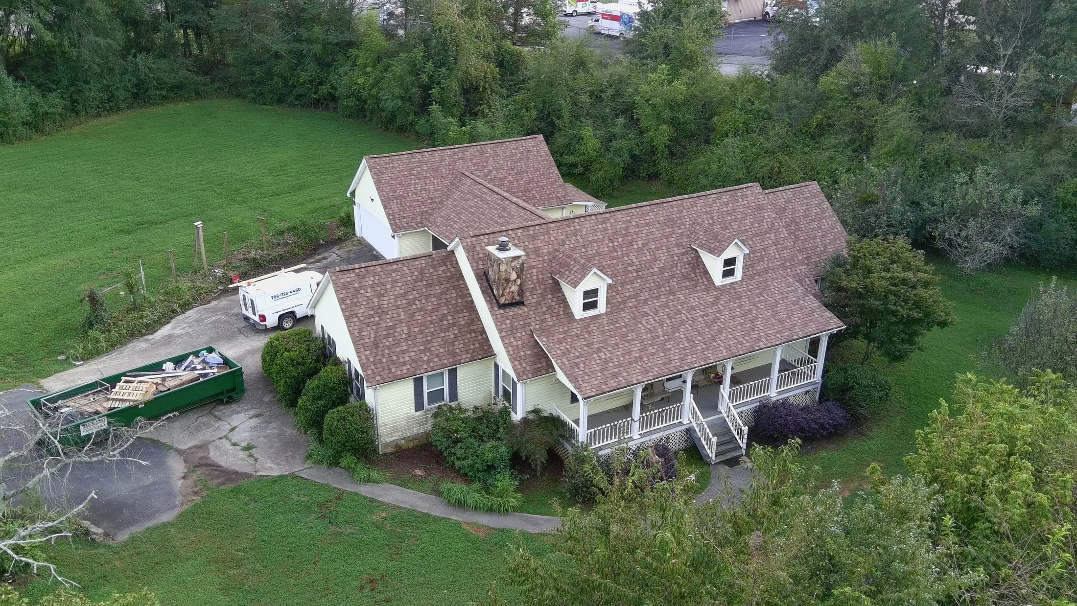 New brown architectural shingle roof on a home with dormers and a front porch, Iron Ridge truck in the driveway