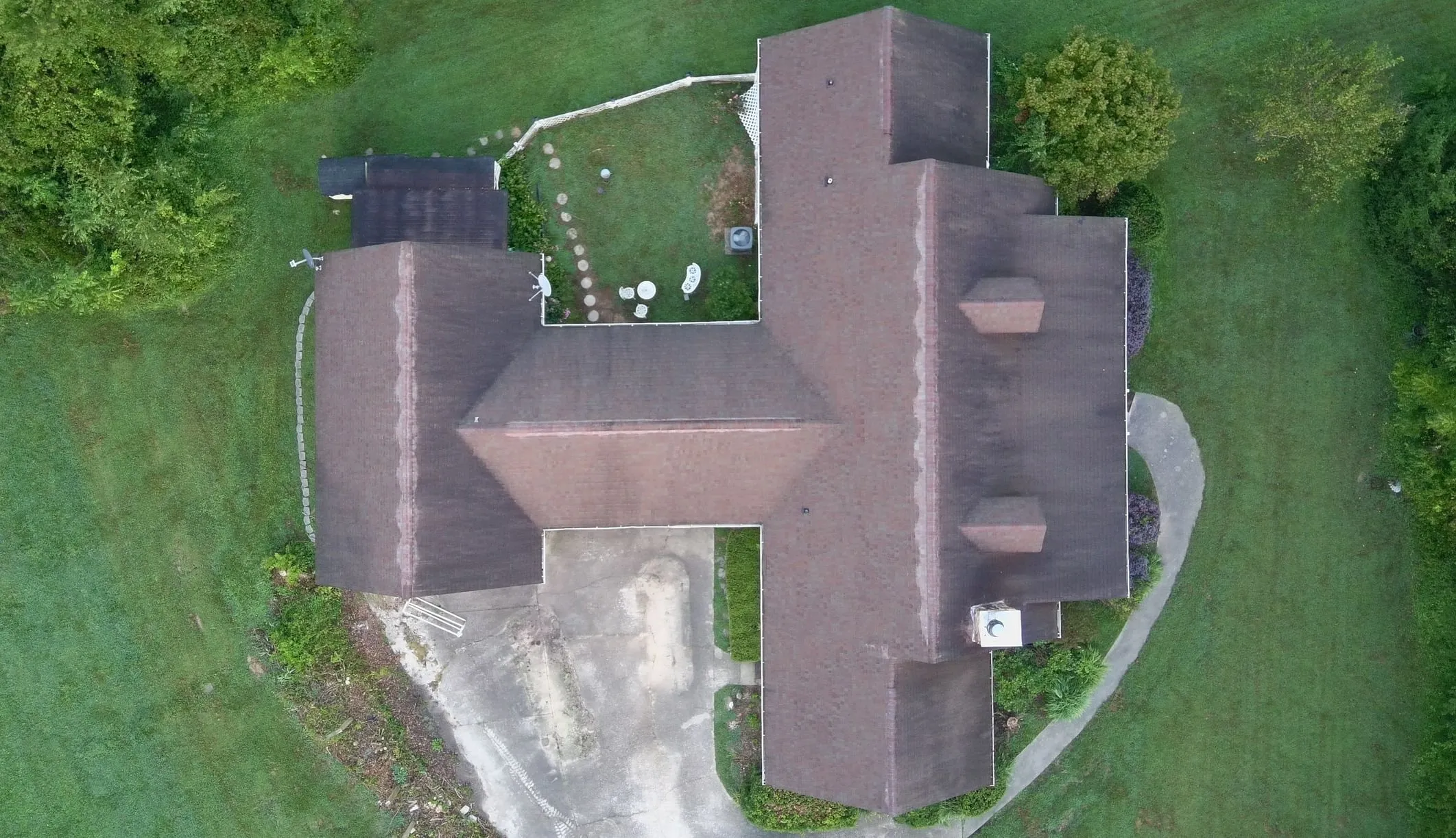 Top-down drone view of the home before replacement, with its old, weathered and stained shingle roof